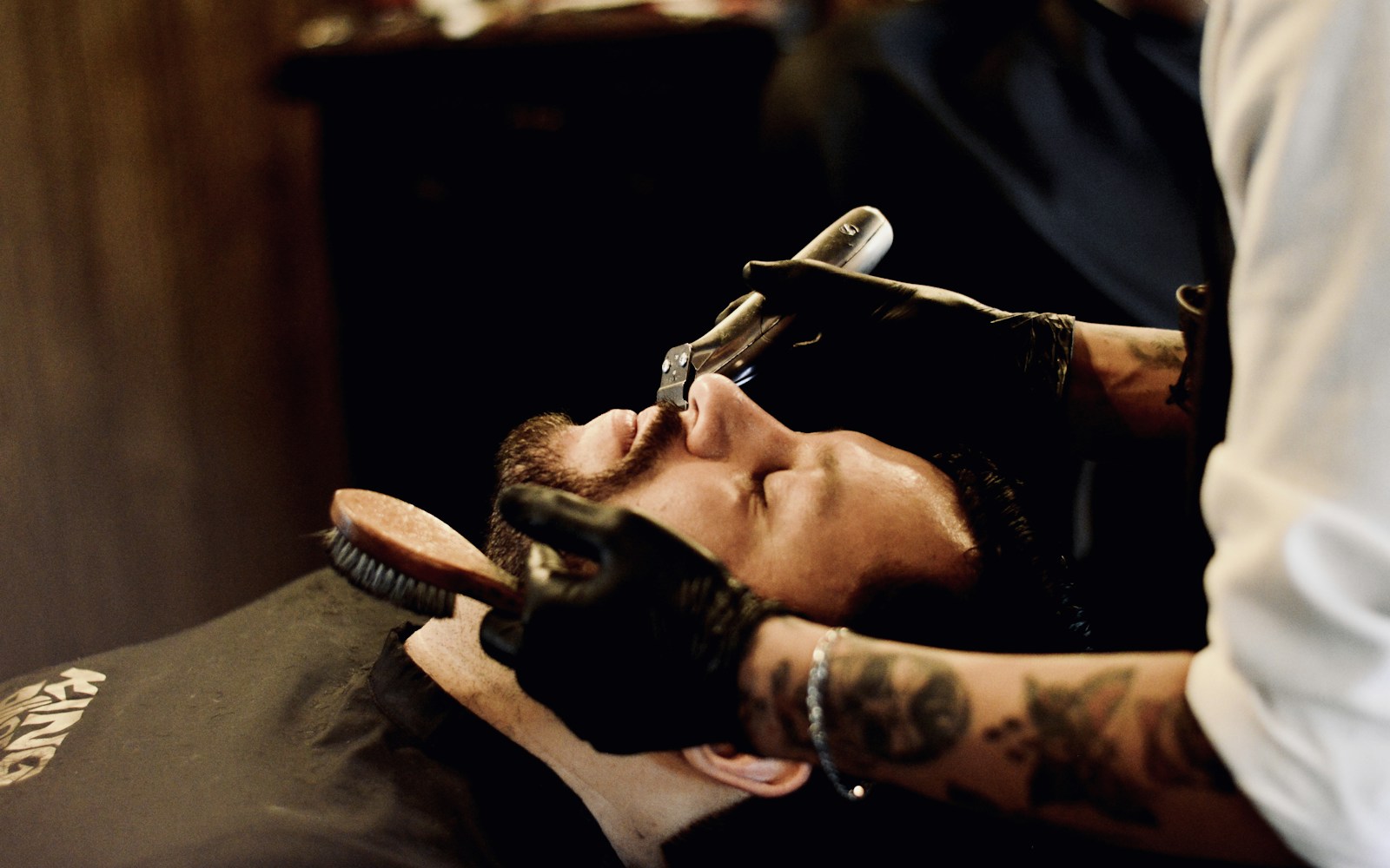 Barbero con guantes realizando servicio con navaja profesional